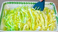 someone using a fork to cut up cabbage in a white dish with green trimmings