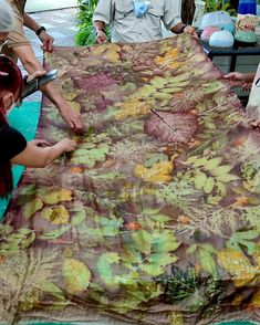 a group of people standing around a table covered in a large cloth with flowers on it