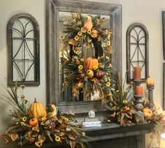 a mantel decorated with pumpkins, flowers and greenery in front of a mirror