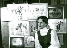 a black and white photo of a woman in front of paintings