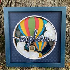 a colorful hot air balloon with the word explore on it in a blue frame next to a tree