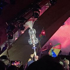 a person holding an umbrella in front of a crowd at a music concert on stage