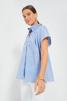 Effortlessly chic, the Rae Blouse takes everything we love about a classic button down and elevates it with fun, feminine details. Featuring a high neck ruffle collar, short cap sleeves, a button front placket, and a simple yet chic chambray fabric, this blue shirt pairs well with denim and flats for daytime and gold jewelry for dining out with friends. Ruffle collar Short cap sleeves Button front placket Gathered back Relaxed fit Chambray fabric Material: 70% Cotton, 30% Linen Care: Hand wash c Casual Top With Ruffled Collar And Button Closure, Casual Tops With Button Closure And Ruffled Collar, Relaxed Fit Blouse With Ruffled Collar, Chic Short Sleeve Blouse For Casual Gatherings, Casual Tops With Ruffled Collar For Daywear, Casual Blouse With Ruffled Collar For Daywear, Short Sleeve Blouse With Button Closure For Casual Gatherings, Chic Collared Blouse For Casual Gatherings, Neck Ruffle Collar