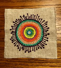 a piece of cloth with an image of a colorful circle on it, sitting on top of a wooden table