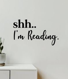 the words shh i'm reading are written in black on a white wall