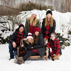 a group of people sitting on top of a wooden bench in front of snow covered ground