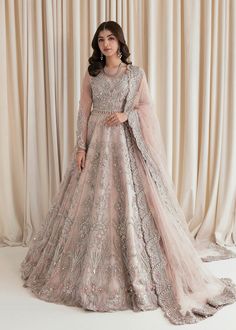 a woman standing in front of a curtain wearing a pink gown and matching with a veil