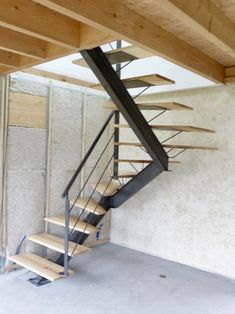 a wooden stair case with metal handrails in an unfinished room next to a wall