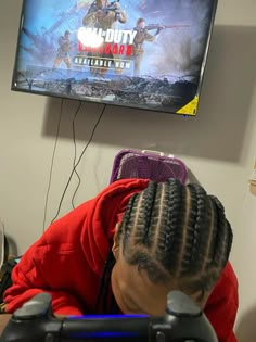 a woman with braids on her head is playing a video game in front of a flat screen tv