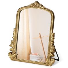 an ornate gold framed mirror with a cross in the middle and a basket under it