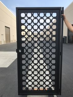 a person holding up a black gate with circles on it in front of a building