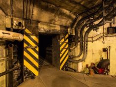 the inside of a building with pipes and yellow caution signs on it's walls