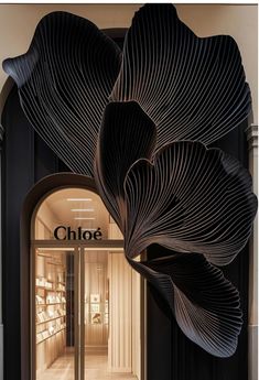 the entrance to a shoe store with large black leaves hanging from it's ceiling