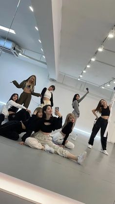 a group of young women sitting on the floor in front of a white wall and ceiling