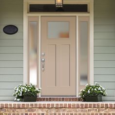 the front door of a house with two planters on either side and one light above it