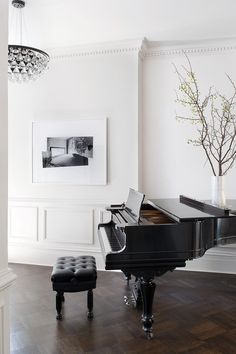 a grand piano in a white room with wood flooring