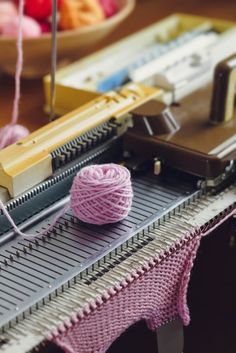 a pink ball of yarn sitting on top of a table next to a sewing machine