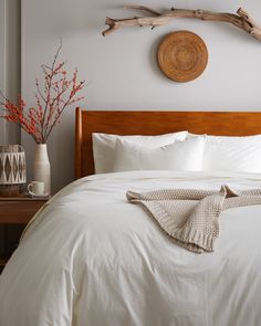 a bed with white linens and pillows in a bedroom next to a wooden headboard