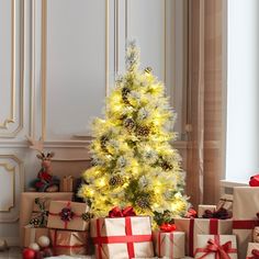 a small christmas tree surrounded by presents under a white and gold decorated ceiling with lights