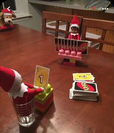 two elfs are sitting at a table with candy bars and cards in front of them