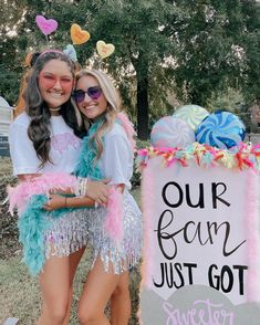 two girls dressed in costumes standing next to a sign that says our fun just got sweeter