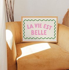 a sign that says la vie est belle sitting on top of a couch in front of a window