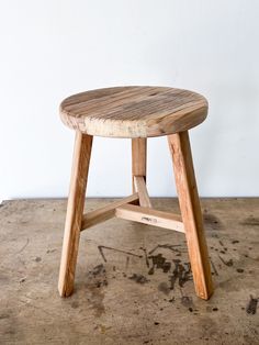 a wooden stool sitting on top of a cement floor