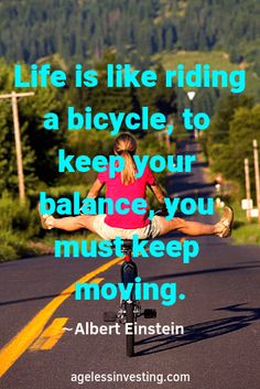 a woman riding a bicycle down the middle of a road with trees in the background