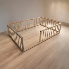 an empty room with wood floors and wooden railings on the floor, in front of a white wall