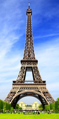 the eiffel tower is very tall and has many people standing around in front of it