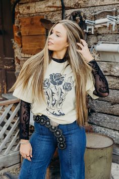 Get wild in The Stetson Tee. With its cropped length and cowboy boots and roses graphic, you'll be the most stylish cowgirl in the room. Made from soft and breathable 100% cotton, this vanilla colored western tshirt is perfect for all your adventures. Haylee is wearing size small paired with The Delmer Jeans , the Bryan Belt and The Annie Mesh Top Graphic Tshirt And Skirt, Simple Cowgirl Outfits Casual, Western Button Up Shirt Outfit, Western Tshirt Outfits, Mesh Long Sleeve Top Outfit Layered, Long Sleeve Lace Top Outfit, Country Shirt Ideas Vinyl, Mesh Undershirt Outfit, Black Lace Shirt Outfit