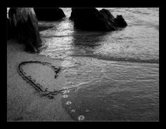 a heart drawn in the sand next to some rocks and water with words written on it