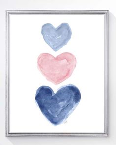 three watercolor hearts in blue, pink and white on a wooden floor with a white frame