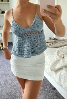 a woman taking a selfie with her cell phone in front of her face and wearing a blue tank top