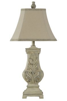 a white lamp with a beige shade on it's base and a bird sitting on top