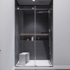 a walk in shower sitting next to a white box on the floor with a black tiled wall