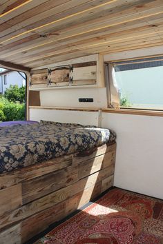 a bed sitting inside of a wooden room next to a window on top of a rug