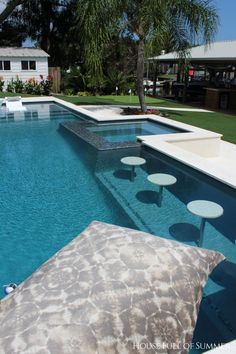 an empty swimming pool in the middle of a lawn area with tables and chairs around it