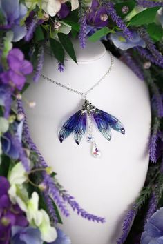 a white mannequin with purple flowers surrounding it and a butterfly pendant hanging from the neck