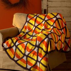 a couch with a blanket on top of it in front of a red and orange wall