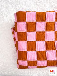 a pink and brown checkerboard quilt on a bed