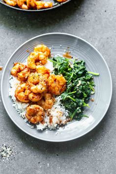 two plates with shrimp, rice and spinach on them