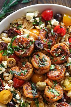 pasta salad with shrimp, olives, tomatoes and feta cheese in a white bowl