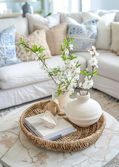 a living room with white furniture and flowers in a vase on top of the coffee table