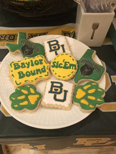 some decorated cookies on a white plate with green and yellow lettering that says baylor bound