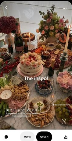 a table filled with lots of food next to a bottle of wine and some candles