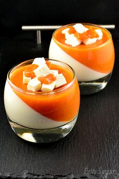 two desserts with orange and white toppings in small glasses on a black surface