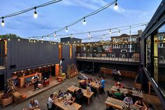 an outdoor restaurant with lots of tables and people sitting around it at dusk or dawn