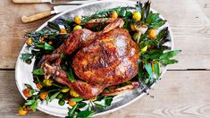 a roasted turkey on a platter surrounded by vegetables and utensils, ready to be served