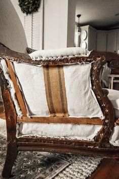 an old wooden chair with white and brown pillows on it's armrests